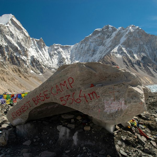 Everest Base Camp marker surrounded by mountains and prayer flags in Nepal