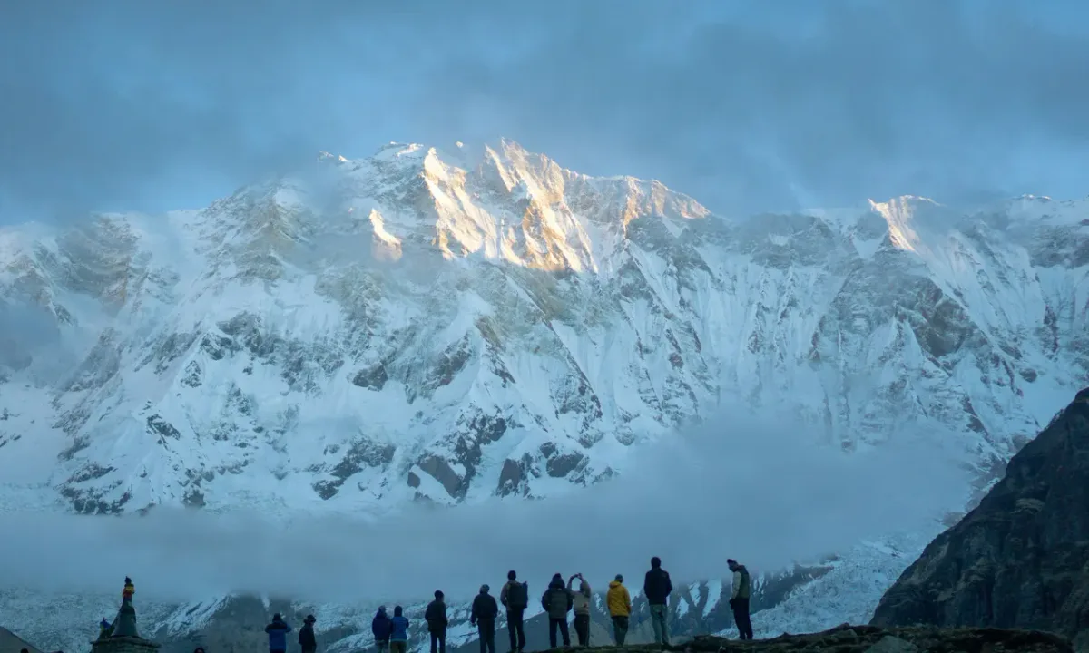 Hikers gaze at snow-capped Annapurna mountain range at sunrise.