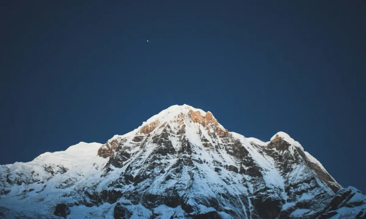Snow-capped Annapurna mountain peak against a dark blue sky.