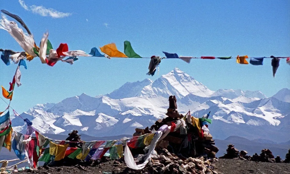 Colorful Tibetan prayer flags fluttering with snow-capped Himalayan peaks in the background during Pikey Peak Trek, Nepal