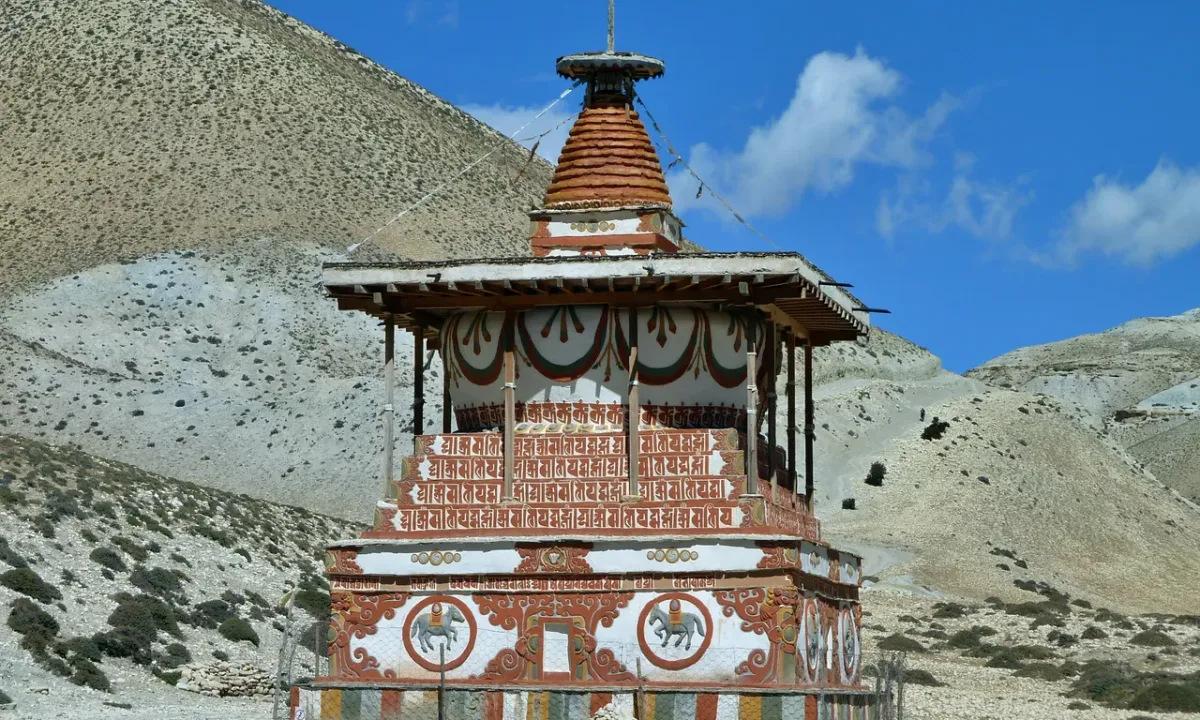 Ancient Buddhist chorten (stupa) with whitewashed walls and colorful decorations against arid rocky mountains in Upper Mustang, Nepal