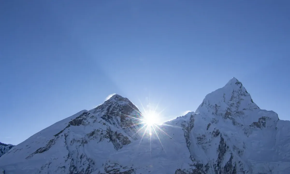 Mount Everest summit piercing through blue sky with sunburst, view from Khumbu region Nepal