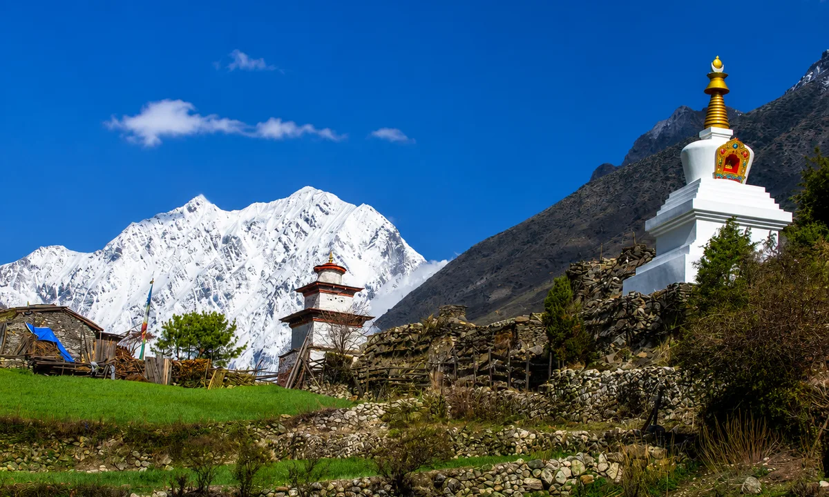 Ancient Buddhist stupa with snow-capped Manaslu peaks, Manaslu fastpacking route Nepal