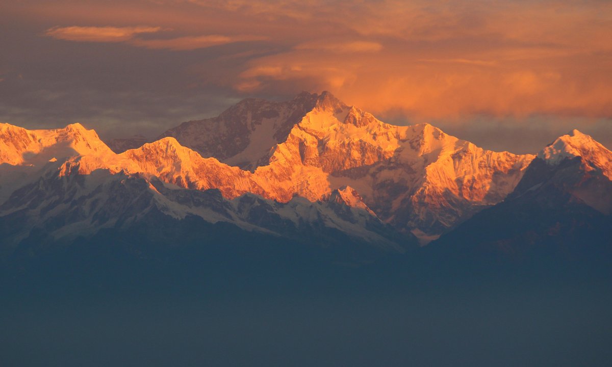 Kanchenjunga massif at sunset, orange golden glow on snow peaks  Kanchenjunga 8586m massif bathed in golden sunset light far eastern Nepal Taplejung Sikkim border