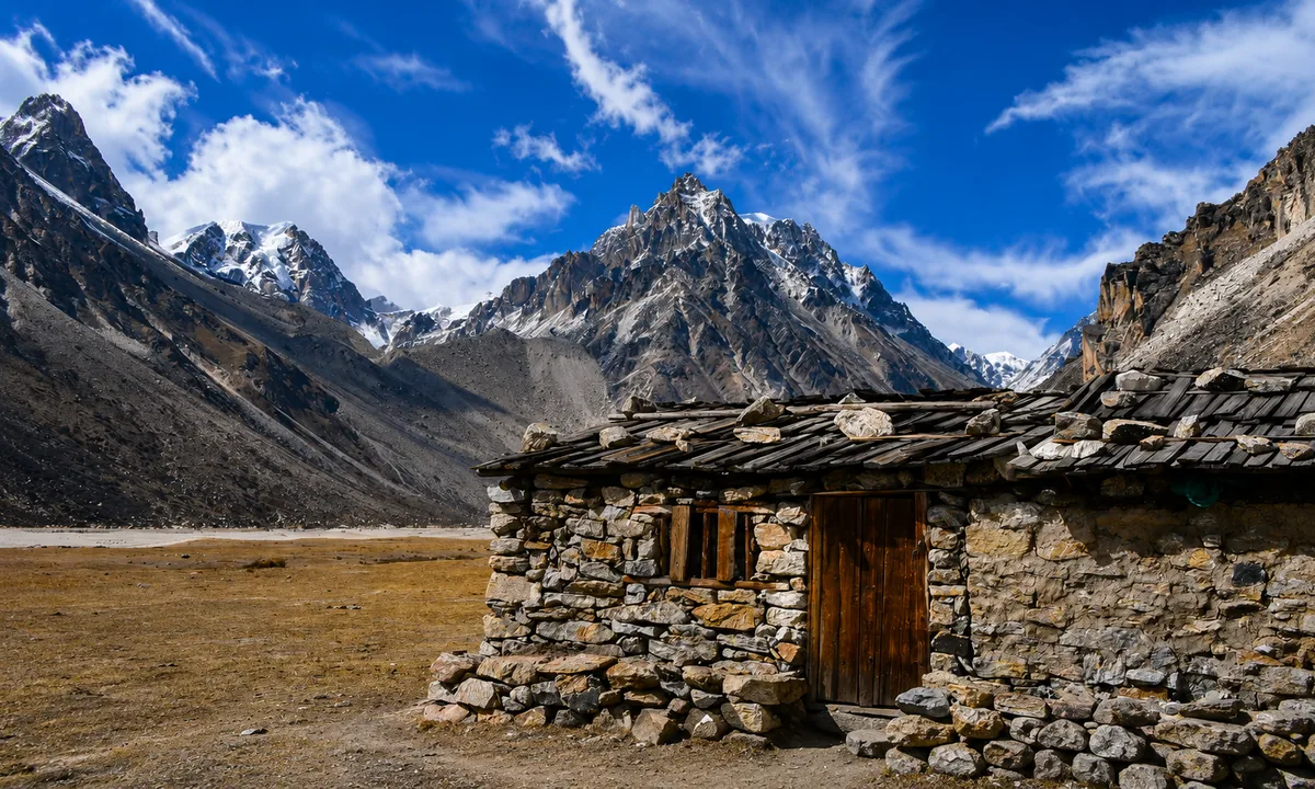 Stone teahouse, Jannu/Kumbhakarna peak, open alpine valley, blue sky  Traditional stone teahouse at Kambachen with Jannu Kumbhakarna peak and blue sky Kanchenjunga Trek Nepal