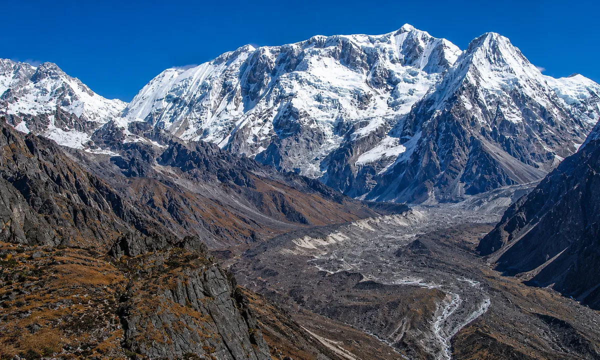 Wide glacial valley, towering peaks both sides, North Base Camp approach  Wide glacial valley with towering snow capped peaks on Kanchenjunga Circuit Trek approach to North Base Camp