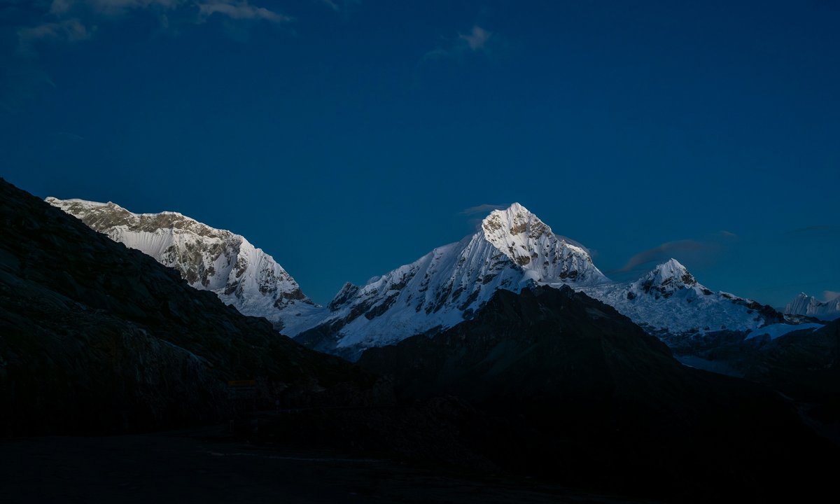 Annapurna Base Camp trek at dusk, snow peaks silhouetted against a deep blue Himalayan sky