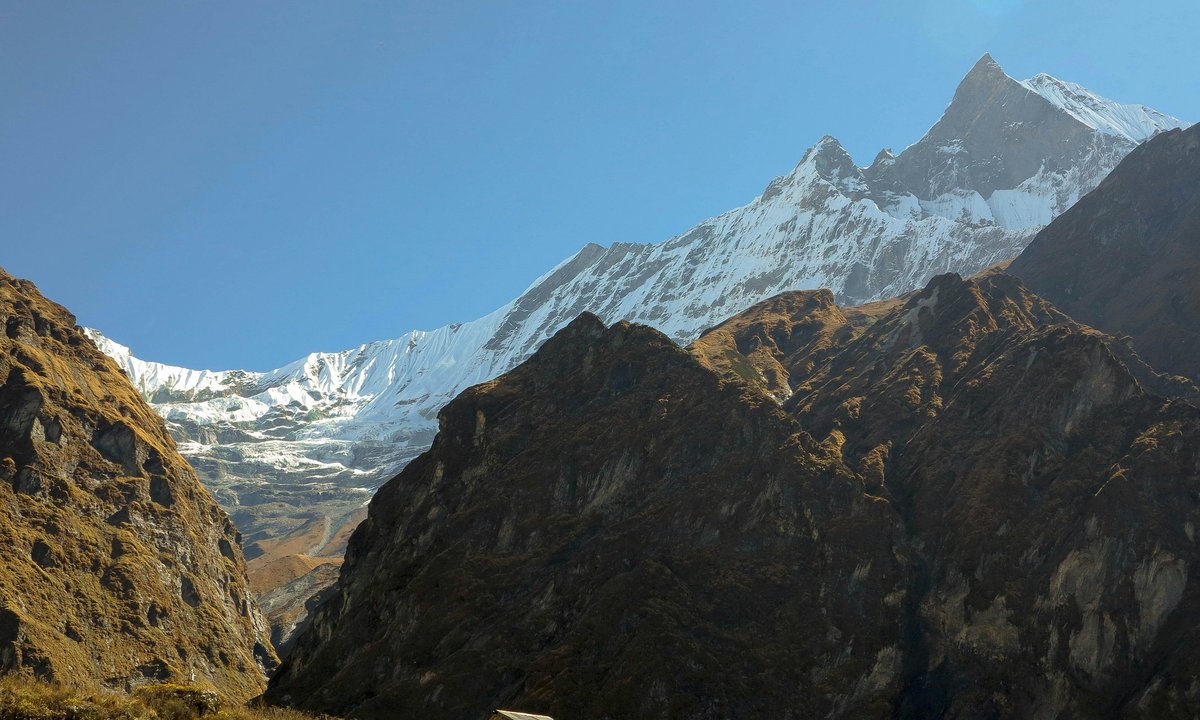 Snow capped Annapurna ridge with glacier ice under clear blue sky on the ABC trek