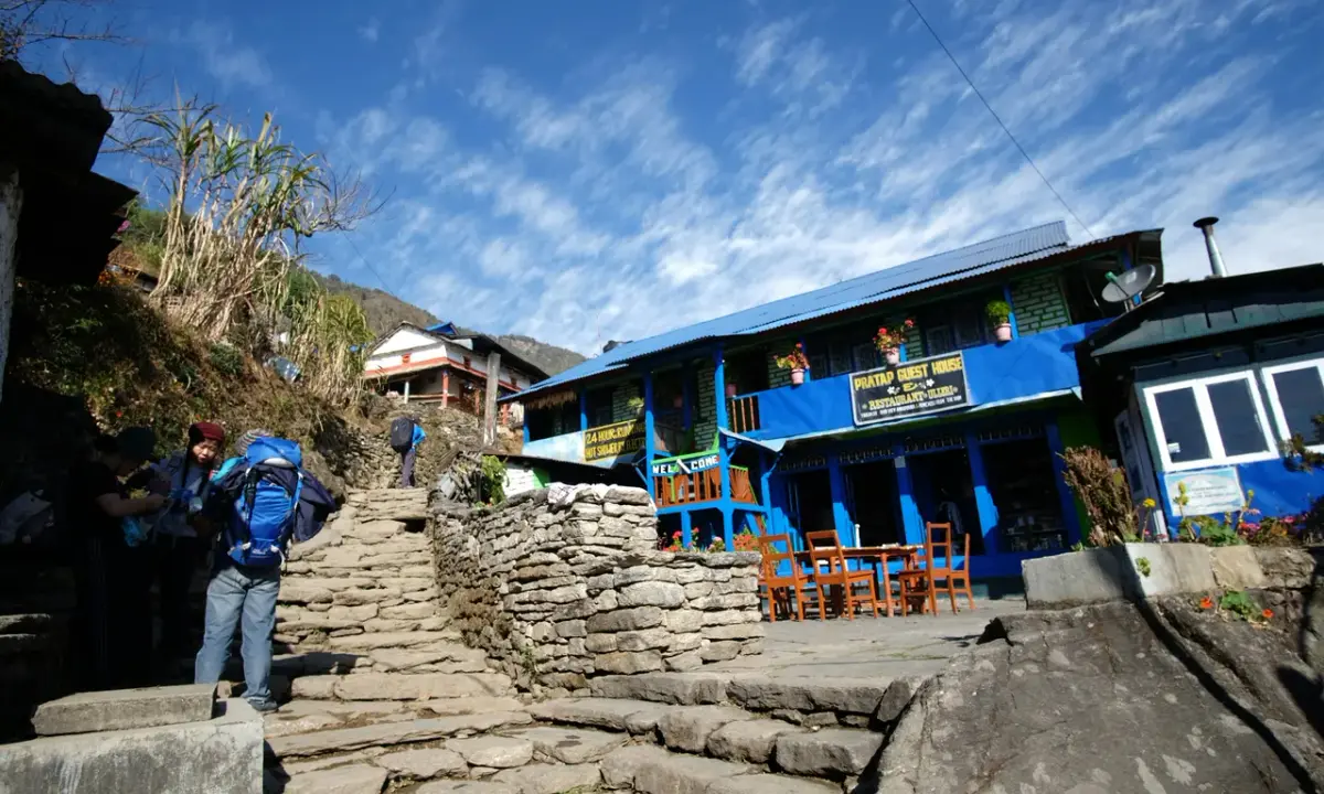 Trekkers with backpacks at stone staircase teahouse guesthouse village trail Annapurna Base Camp trek Nepal