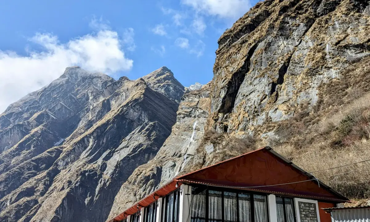 Teahouse lodge beneath dramatic rocky cliffs steep mountain walls Annapurna Base Camp trek route Nepal