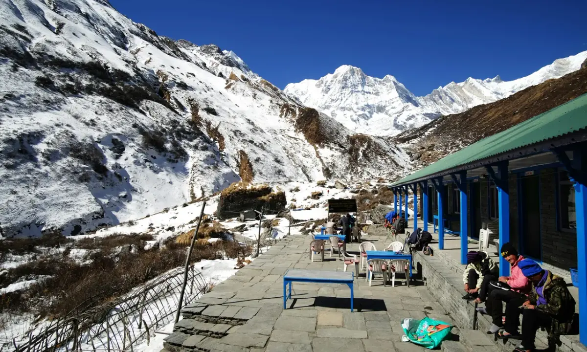 Trekkers resting at teahouse terrace snowy Annapurna mountain valley Annapurna Base Camp 4130m Nepal winter