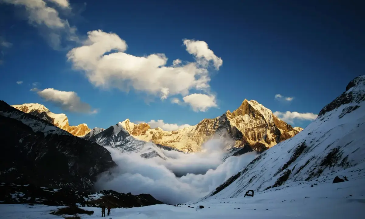 Two trekkers standing in deep snow Annapurna massif golden clouds rolling valley Annapurna Base Camp trek Nepal
