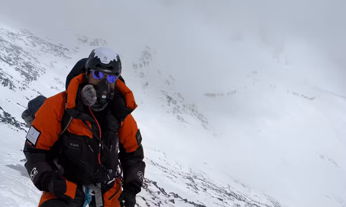 Sudhigya Pant climbing Everest through cloud and fog with his brand Kapi visible on his jacket — upper mountain section, May 2026