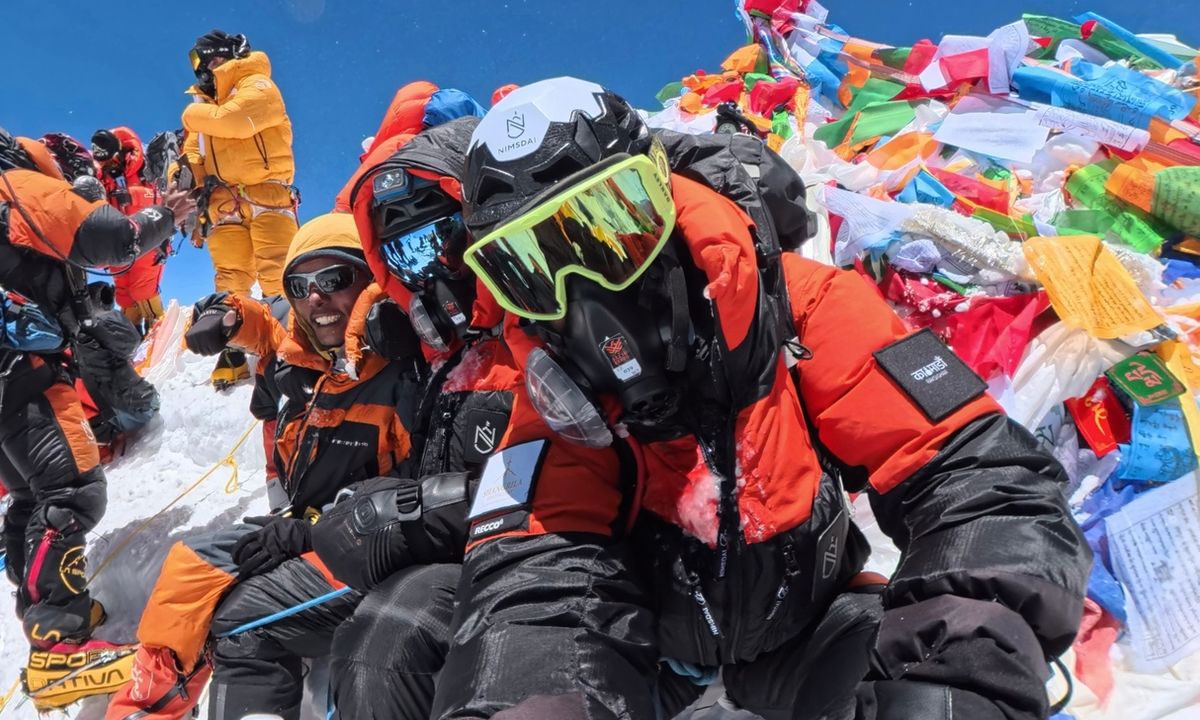 Sudhigya Pant celebrating at the summit of Mount Everest with his sherpa Gyalzen, laughing among prayer flags at 8,849 metres on May 20, 2026