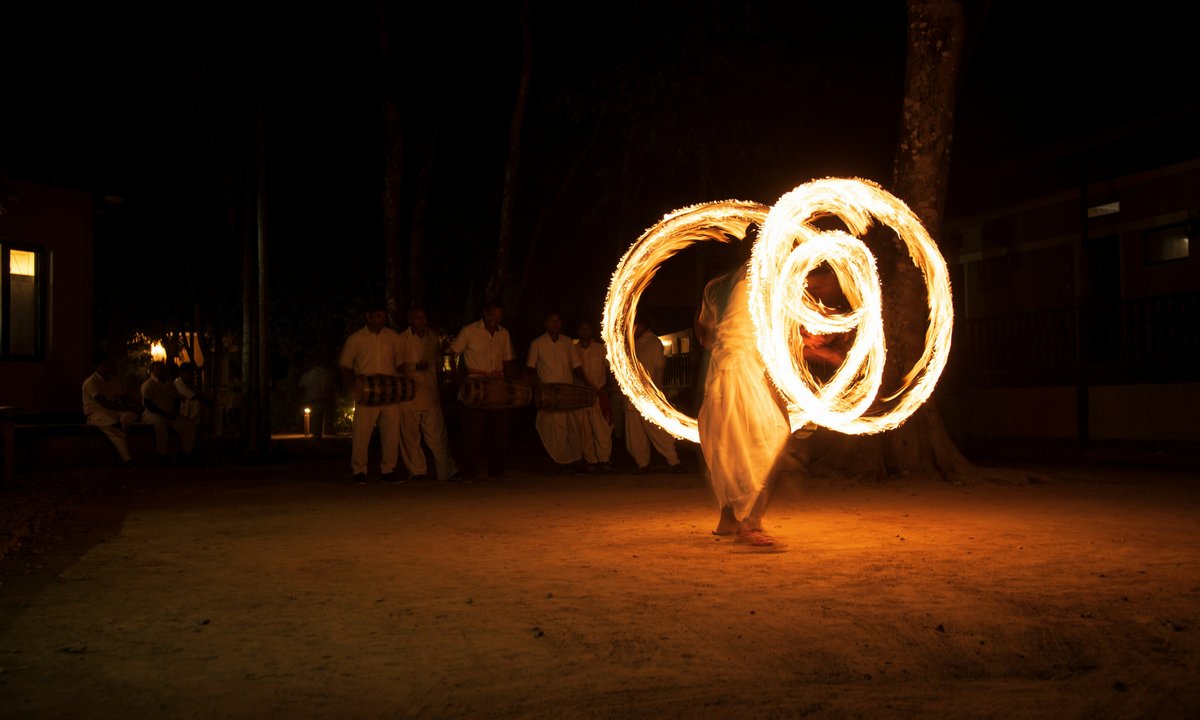 Traditional fire dancer performing at night during a cultural festival in Nepal, creating glowing circular trails of fire against a dark sky