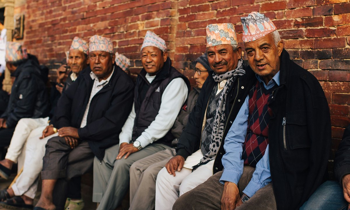 Group of Nepali men in traditional dhaka topi sitting together, representing the diverse ethnic communities of Nepal
