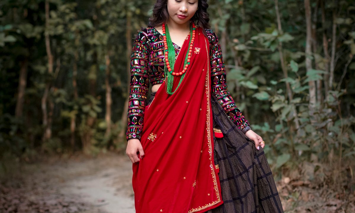 Magar woman in traditional red cloth and black embroidered jacket with colourful beaded necklaces in Nepal