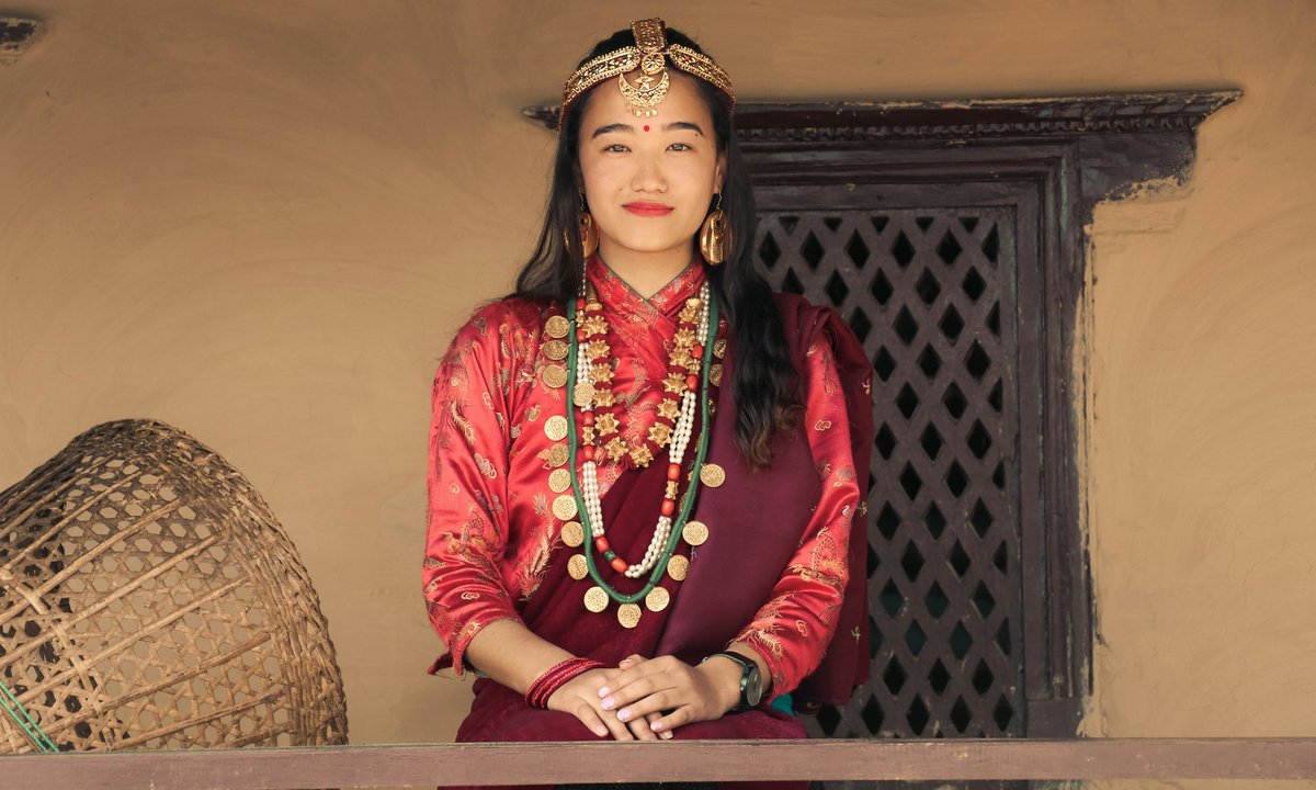 Gurung woman in traditional red dress with gold coin necklace and traditional head ornament in Nepal