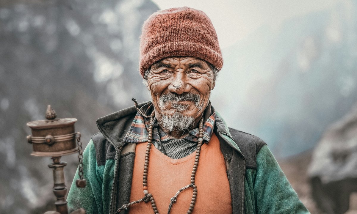 Sherpa elder holding a traditional Buddhist prayer wheel in the Everest region of the Khumbu valley, Nepal