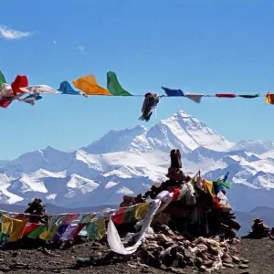 Colorful Tibetan prayer flags fluttering with snow-capped Himalayan peaks in the background during Pikey Peak Trek, Nepal
