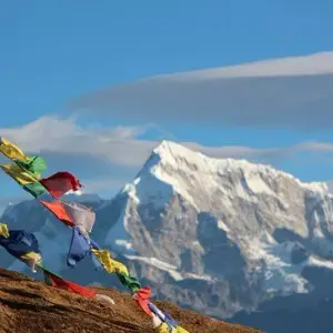 Traditional Buddhist prayer flags blowing in wind with majestic Himalayan mountain range and clouds on Pikey Peak Trek route