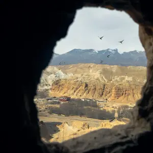 View through ancient cave entrance overlooking vast canyon landscape and arid valleys of Upper Mustang, Nepal