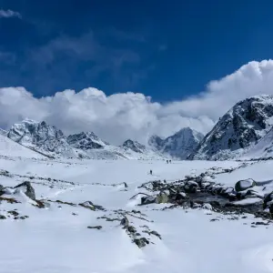 Trekker crossing Cho La Pass in winter snow with dramatic Himalayan mountain backdrop, Everest Three Passes Trek Nepal