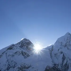 Mount Everest summit piercing through blue sky with sunburst, view from Khumbu region Nepal