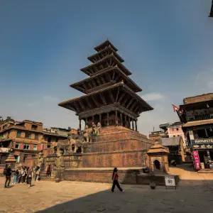 A wide-angle view of the five-story Nyatapola Temple in Bhaktapur, Nepal, showing its towering pagoda structure and the stone guardians lining its steep central staircase.