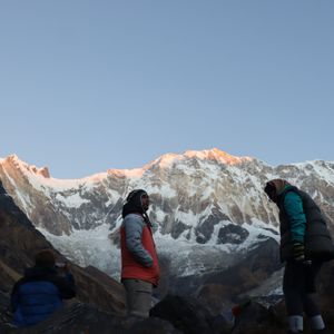 Trekker standing at Annapurna Base Camp at sunrise with towering snow peaks behind, Nepal