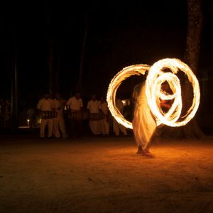 Traditional fire dancer performing at night during a cultural festival in Nepal, creating glowing circular trails of fire against a dark sky