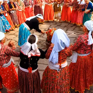 Women in traditional red Nepali hill community dress holding hands in a large circle deuda dance at an outdoor cultural gathering in Nepal