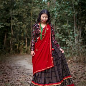 Magar woman in traditional red cloth and black embroidered jacket with colourful beaded necklaces in Nepal