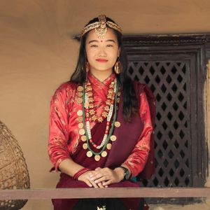 Gurung woman in traditional red dress with gold coin necklace and traditional head ornament in Nepal