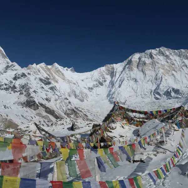 Prayer flags flutter against snow-covered Annapurna mountains in Nepal.