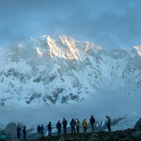 Hikers gaze at snow-capped Annapurna mountain range at sunrise.