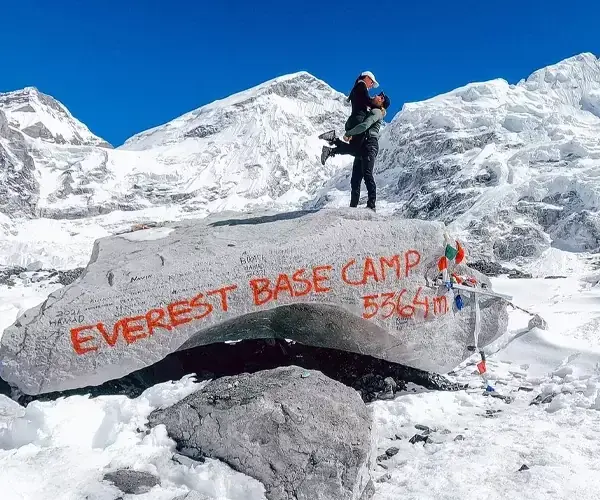 Couple embraces at Everest Base Camp, 5364m, with snowy peaks.