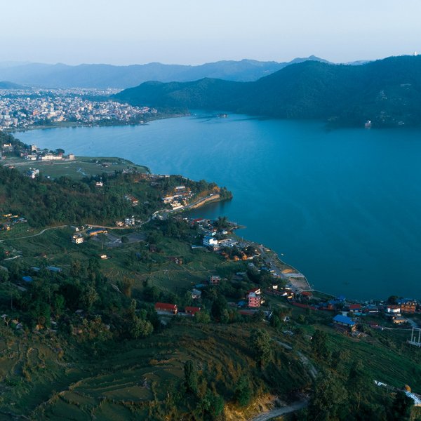 Aerial view of a Himalayan lake surrounded by green hills and mountain villages